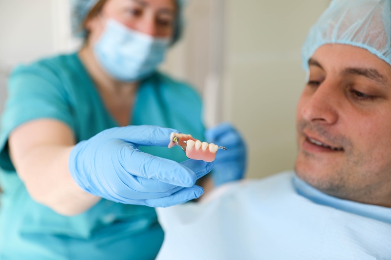 Dental professional presenting an implant-supported denture model to a patient in Mokena, IL